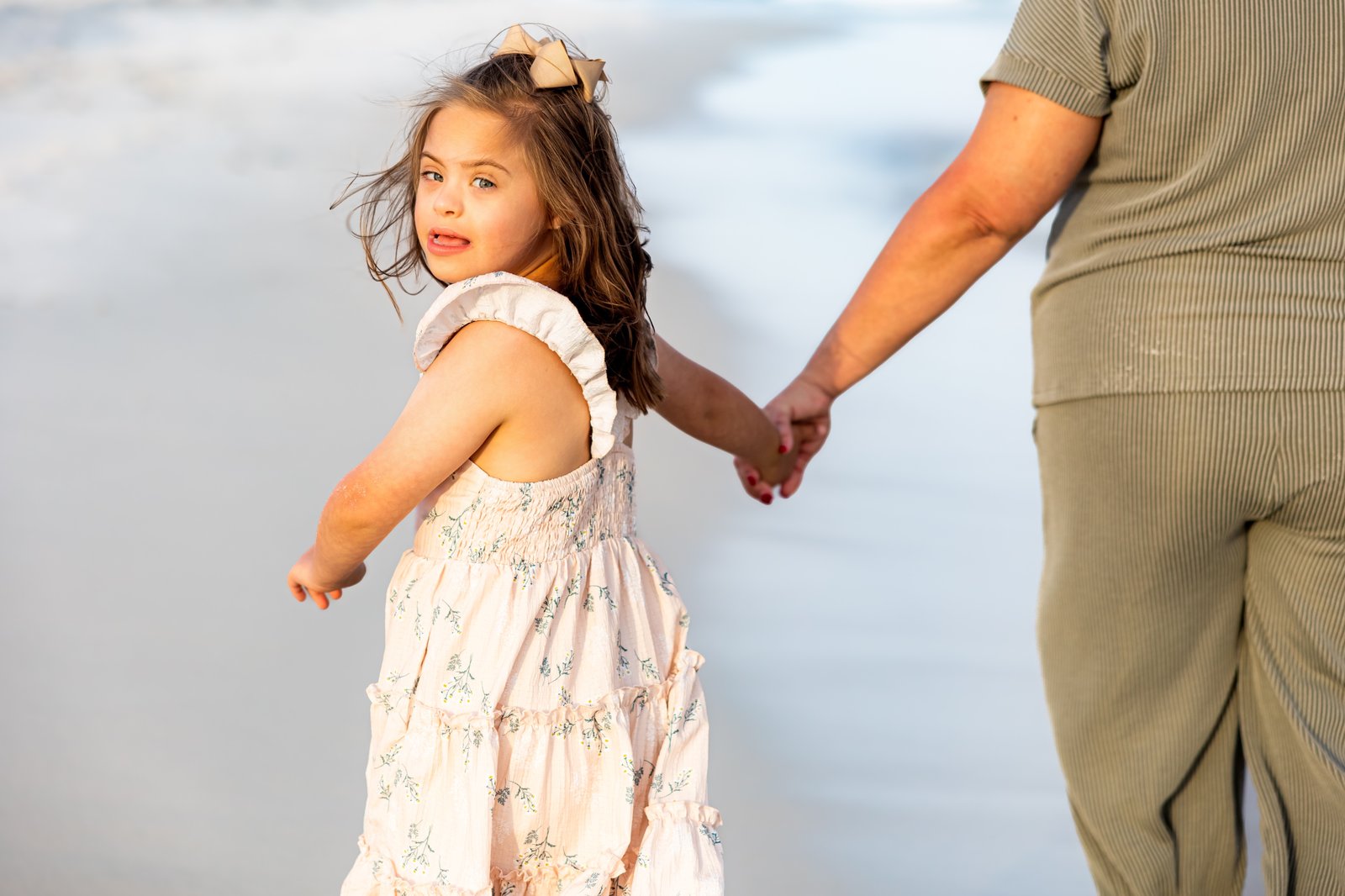 A mother and her daughter walking hand in hand along the shore